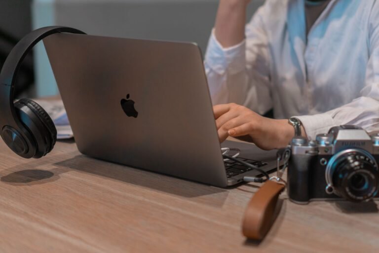 Close-up of a person working remotely with a laptop, headphones, and camera. Ideal for tech and lifestyle themes.